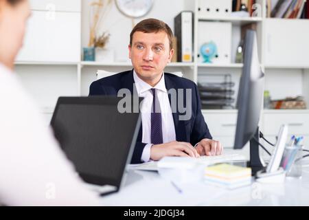 Geschäftsmann, der mit einer Kollegin im Büro arbeitet Stockfoto