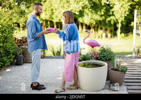 Der Mann schenkt seiner Frau ein Geschenk in einer rosa Schachtel und feiert im Freien Stockfoto