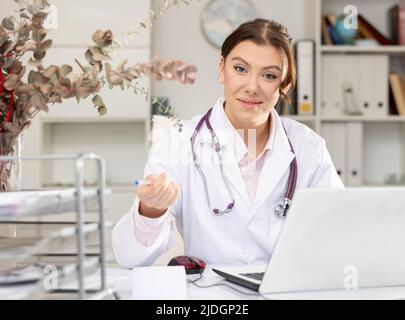 Porträt einer Ärztin, die mit Laptop und Dokumenten arbeitet Stockfoto