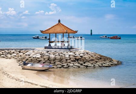 Holzpavillon mit Bambusdach auf Felsen getty am Rande der Strandküste in Bali, Indonesien, blauem Ozean und Booten, die in der Ferne schwimmen Stockfoto