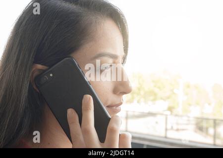 Seriöse Geschäftsfrau, junge tausendjährige kaukasische seriöse Geschäftsfrau, die am Telefon hört. Hält das Mobiltelefon und führt geschäftliche Anrufe durch. Stockfoto