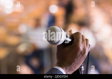 Mikrofon mit männlicher Hand im Konferenzsaal Stockfoto
