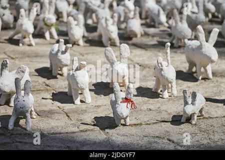 Weiße Kaninchenstatuen aus Gips bei der Kunstausstellung im Freien, künstliche weiße Hasen auf der Straße der Stadt. Viele weiße handgemachte Kaninchen, viele dekorativ Stockfoto