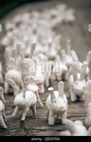 Weiße Kaninchenstatuen aus Gips bei der Kunstausstellung im Freien, künstliche weiße Hasen auf der Straße der Stadt. Viele weiße handgemachte Kaninchen, viele dekorativ Stockfoto