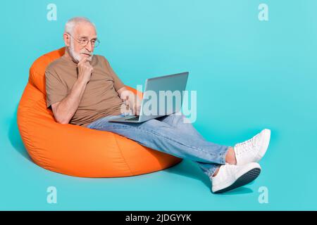 Porträt eines hübschen trendigen fokussierten grauhaarigen Mannes mit Laptop Studium isoliert über hellen blauen Hintergrund Stockfoto