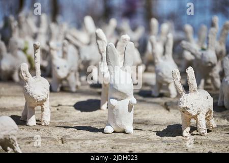 Weiße Kaninchenstatuen aus Gips bei der Kunstausstellung im Freien, künstliche weiße Hasen auf der Straße der Stadt. Viele weiße handgemachte Kaninchen, viele dekorativ Stockfoto