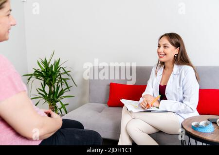 Die junge, schöne Ernährungswissenschaftlerin berät ihre Patientin in ihrer Klinik. Hochwertige Fotos Stockfoto