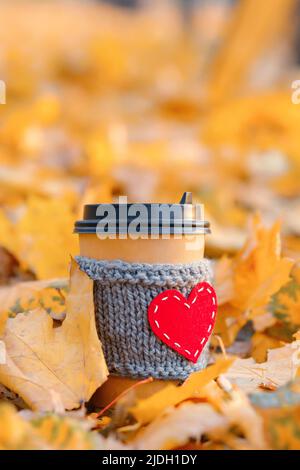 Papierkaffee gemütliche Tasse mit Herzform in Herbstblättern, vertikaler Kopierraum Stockfoto