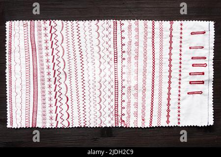 Baumwolltuch mit Nähmaschinenstichmustern auf dunklem Holztisch Stockfoto