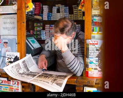 Mann im Kiosk beim Lesen einer Zeitung, Portugal, Lissabon Stockfoto