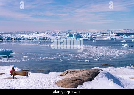 ilulissat Landschaft mit Meer und Eisbergen Touristenfrau auf einer Bank Stockfoto