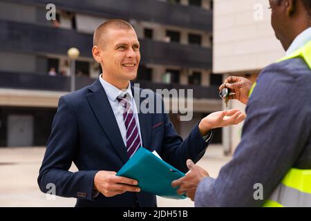 Ingenieur, der den Menschen Schlüssel für eine neue Wohnung gab Stockfoto