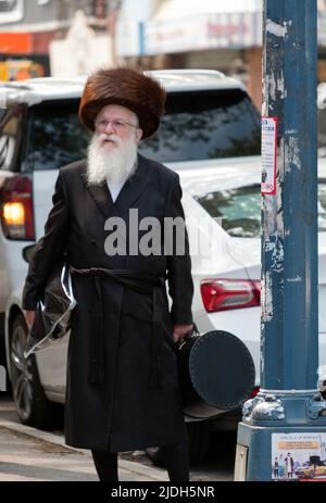 Ein orthodoxer jüdischer Mann, wahrscheinlich ein Rabbi, trägt seinen Stielpelzhut zu einer Familienfeier, wahrscheinlich zu einer Hochzeit. In Williamsburg, Brooklyn, New York City Stockfoto
