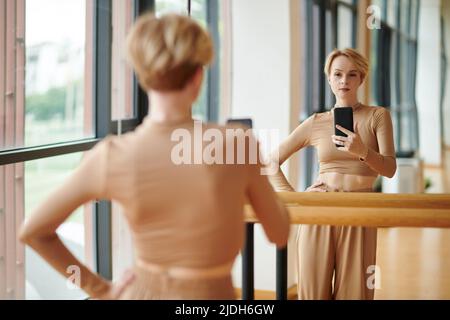 Fit weibliche Tänzerin Langarm Oberteil und breite Hosen Aufnahme Selfie im Studio Spiegel Stockfoto