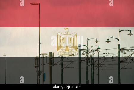 Ägyptische Flagge mit Straßenbahn, die auf einer elektrischen Linie mit blauem Himmel als Hintergrund, elektrischer Eisenbahnzug und Stromleitungen, Kabelverbindungen und mir verbindet Stockfoto