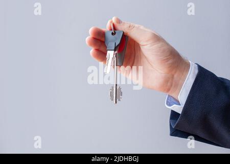 Hausschlüssel in männlicher Hand auf weißem Hintergrund. Immobilienkonzept Stockfoto