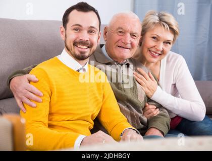 Lächelnde Familie, die sich auf dem Sofa umarmt Stockfoto