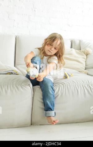 Niedliches Mädchen, das zu Hause eine Socke aufsetzt Stockfoto