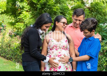 Die Familie hält die Hände der Mutter auf ihrem schwanger werdenden Bauch Stockfoto