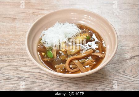 Geschmorte Fischpfote mit Bambusschiessen, die Hühnchen in Scheiben schneiden und gekochtes Ei in einer Suppe mit roter Soße, die Reis vermicelli auf der Schüssel gibt Stockfoto