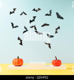 Moderne Produktanzeige auf himmelblauem Hintergrund mit Podium und bunten Herbstkürbissen und Fledermäusen Silhouetten. Geeignet für Produktdisplays und Business Stockfoto