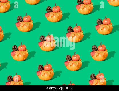Kreatives Herbstmuster aus Kürbissen, Tannenzapfen und Blättern auf grünem Hintergrund. Minimales saisonales Konzept. Halloween oder Thanksgiving Komposition. Stockfoto