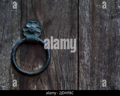 Geschmiedeter Metallring auf einer schweren Holztür, strukturierter Hintergrund in Nahaufnahme Stockfoto