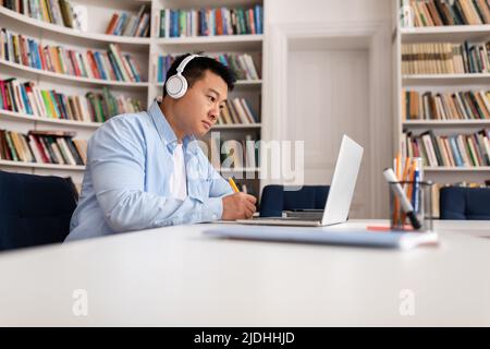 Asiatischer Geschäftsmann, Der Am Laptop Arbeitet Und Notizen Im Bürozimmer Nimmt Stockfoto