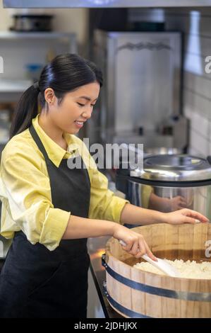 Frau, die in der Küche neben einer Schüssel steht und Essen zubereitet Stockfoto