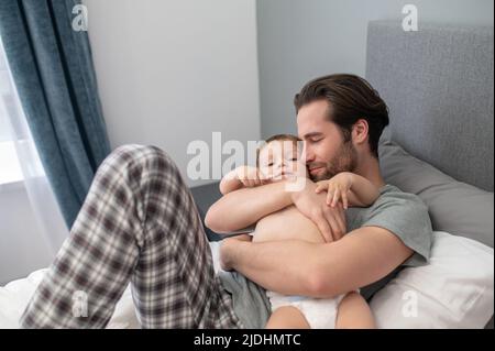 Mann mit geschlossenen Augen liegend umarmend Kind Stockfoto