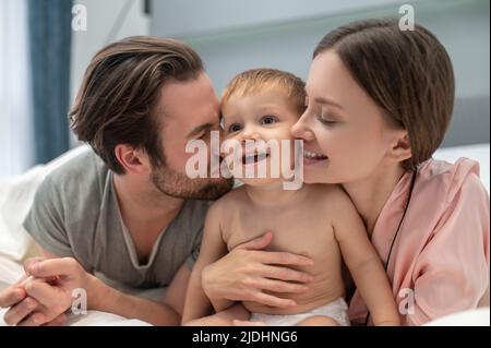 Mann und Frau mit geschlossenen Augen berühren Baby Stockfoto