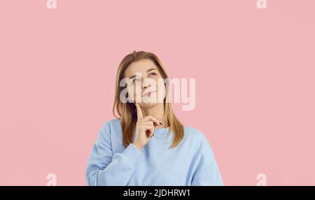 Porträt einer lächelnden jungen, nachdenklichen Frau, die eine coole Idee hat oder etwas Interessantes aufbrachte. Stockfoto