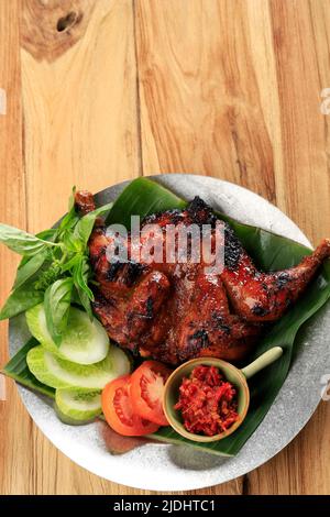 Gebratenes Huhn mit Lalapan, Bakakak Ayam Bakar mit frischem Gemüse, authentisches Rezept von Indonesian Roasted Chicken. Stockfoto