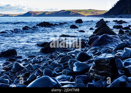 Farbenprächtiges Moody Light auf Wet Rocks, Bucks Mills Beach in High Tide mit Blick auf den Strand und die Küste von North Devon, Bucks Mills, Devon, Stockfoto