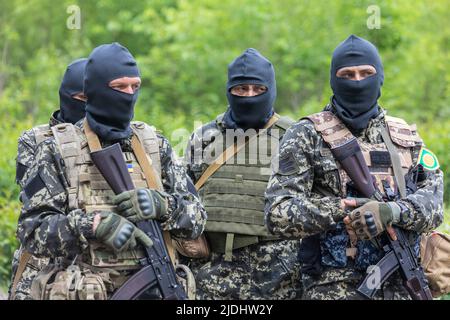 Territoriale Verteidigungskämpfer mit automatischen Gewehren befinden sich während des Kampftrainings in einer Kampfposition. Mitglieder der Gebietsverteidigungseinheit Bucha, einer Hilfskraft der regulären ukrainischen Armee, nehmen an einer Übung für die regulären Kampftaktikklassen Teil, nicht weit von der ukrainischen Stadt Bucha, Region Kiew, Ukraine. Stockfoto