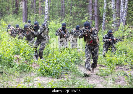 Territoriale Verteidigungskämpfer mit automatischen Gewehren befinden sich während des Kampftrainings in einer Kampfposition. Mitglieder der Gebietsverteidigungseinheit Bucha, einer Hilfskraft der regulären ukrainischen Armee, nehmen an einer Übung für die regulären Kampftaktikklassen Teil, nicht weit von der ukrainischen Stadt Bucha, Region Kiew, Ukraine. Stockfoto