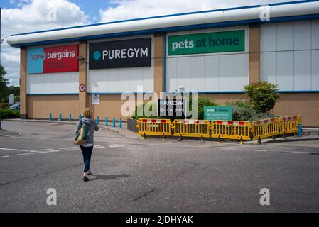 Eine Frau geht zu einem außerhalb der Stadt gelegenen Einzelhandelsstandort in Salisbury Wiltshire UK, wo sie Schilder mit Schnäppchen, einem reinen Fitnessstudio und Haustieren zu Hause zeigt. Stockfoto