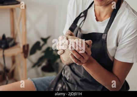 Unverkennbare weibliche Potter-Meisterin bereitet Tonhaufen vor, um in ihrem Keramikstudio einen Topf auf einem Töpferrad zu kreieren Stockfoto