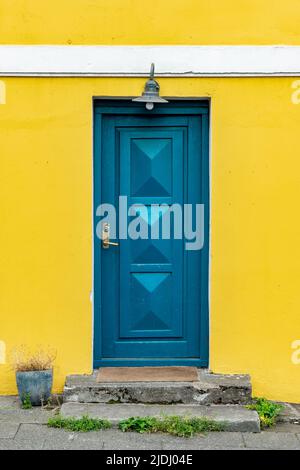 Blaue Tür auf einem gelb gestrichenen bunten Haus, Architekturdetails in Reykjavik, Island Stockfoto