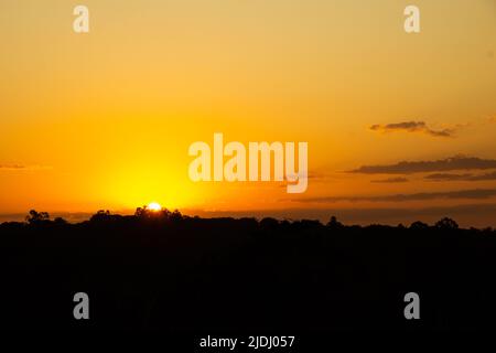 Goiania, Goiás, Brasilien – 19. Juni 2022: Ein wunderschöner goldener Sonnenuntergang am Horizont, von einer Autobahn aus gesehen in der Stadt Goiania. Stockfoto