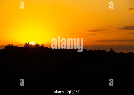 Goiania, Goiás, Brasilien – 19. Juni 2022: Ein wunderschöner goldener Sonnenuntergang am Horizont, von einer Autobahn aus gesehen in der Stadt Goiania. Stockfoto