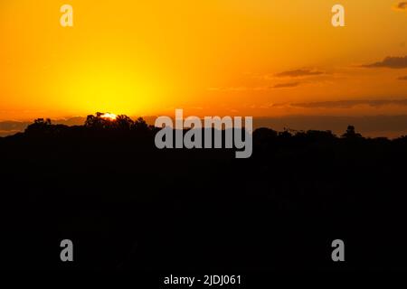 Goiania, Goiás, Brasilien – 19. Juni 2022: Ein wunderschöner goldener Sonnenuntergang am Horizont, von einer Autobahn aus gesehen in der Stadt Goiania. Stockfoto