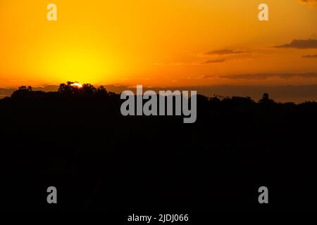 Goiania, Goiás, Brasilien – 19. Juni 2022: Ein wunderschöner goldener Sonnenuntergang am Horizont, von einer Autobahn aus gesehen in der Stadt Goiania. Stockfoto