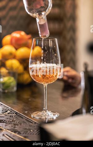 Barkeeper gießt Prosecco in Weinglas. Langes kohlensäurehaltiges Getränk. Stockfoto