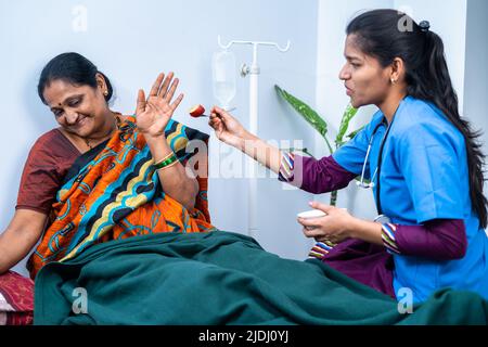 Kranke Patienten mittleren Alters, die Nein sagen, Früchte von der fürsorglichen Krankenschwester im Pflegeheim des Krankenhauses zu essen - Konzept der fürsorglichen, assistenten und beruflichen Tätigkeit Stockfoto
