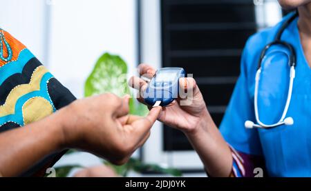 Nahaufnahme Krankenschwester, die Diabetes von kranken Frauen im Alter zwischen 2 und 4 Jahren zu Hause mit Glucometer untersucht – Konzept der routinemäßigen Hausgesundheitsprüfung und Hausmeisterin. Stockfoto