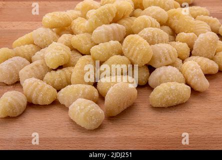 Kartoffelgnocchi roh auf Holztisch, italienische Pasta mit Mehl und Kartoffeln. Ungekochte Knödel Stockfoto