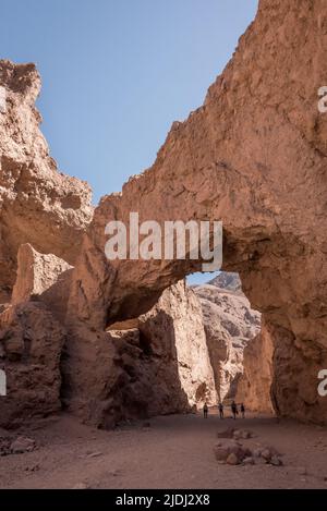 Eine vierköpfige Familie wandert unter dem Natural Bridge Bogen im beliebten Canyon für kurze Tageswanderungen im Death Valley National Park in Kalifornien. Stockfoto