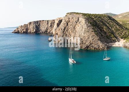 Segelboote in der fjordähnlichen Bucht von Cala Domestica mit dem Sandstrand von Cala Lunga, eingebettet zwischen felsigen Klippen im Südwesten Sardiniens Stockfoto