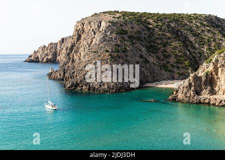 Segelboote in der fjordähnlichen Bucht von Cala Domestica mit dem Sandstrand von Cala Lunga, eingebettet zwischen felsigen Klippen im Südwesten Sardiniens Stockfoto